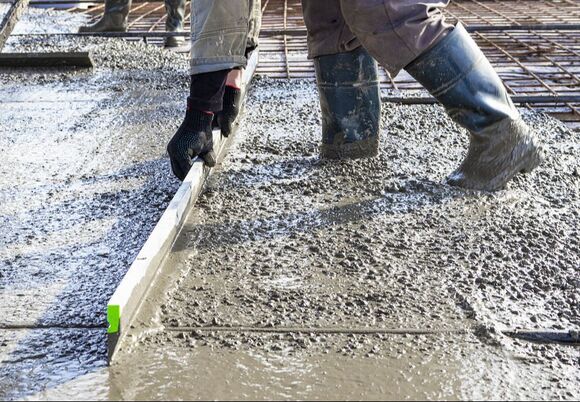 A construction worker in Norwalk, CT, leveling a poured concrete floor in an industrial workshop.