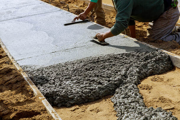 The sidewalk of a newly constructed building in Norwalk, Connecticut, is being laid down in wet concrete.