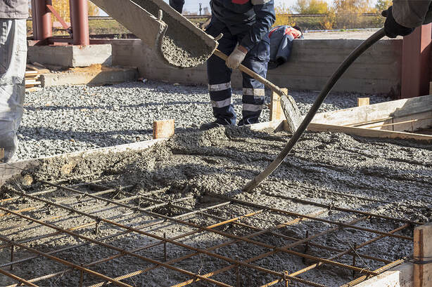 Pouring cement or concrete with a concrete mixer truck, construction site in Norwalk, Connecticut, with a reinforced grillage foundation.