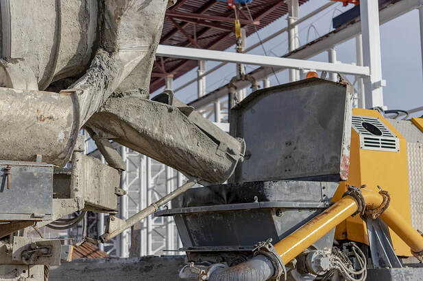 A concrete mixer truck pours mortar into a concrete pump at a construction site in Norwalk, CT. 