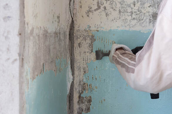 A worker removes paint to repair a wall in an apartment in Norwalk, CT.