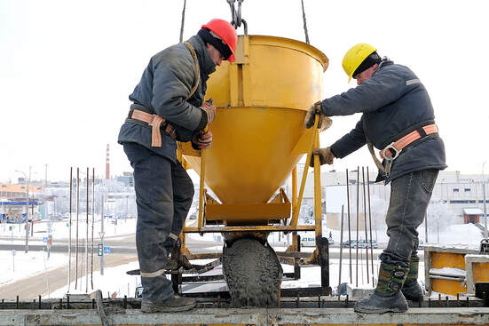 The construction workers at a Norwalk, CT, construction site pour concrete into a form.